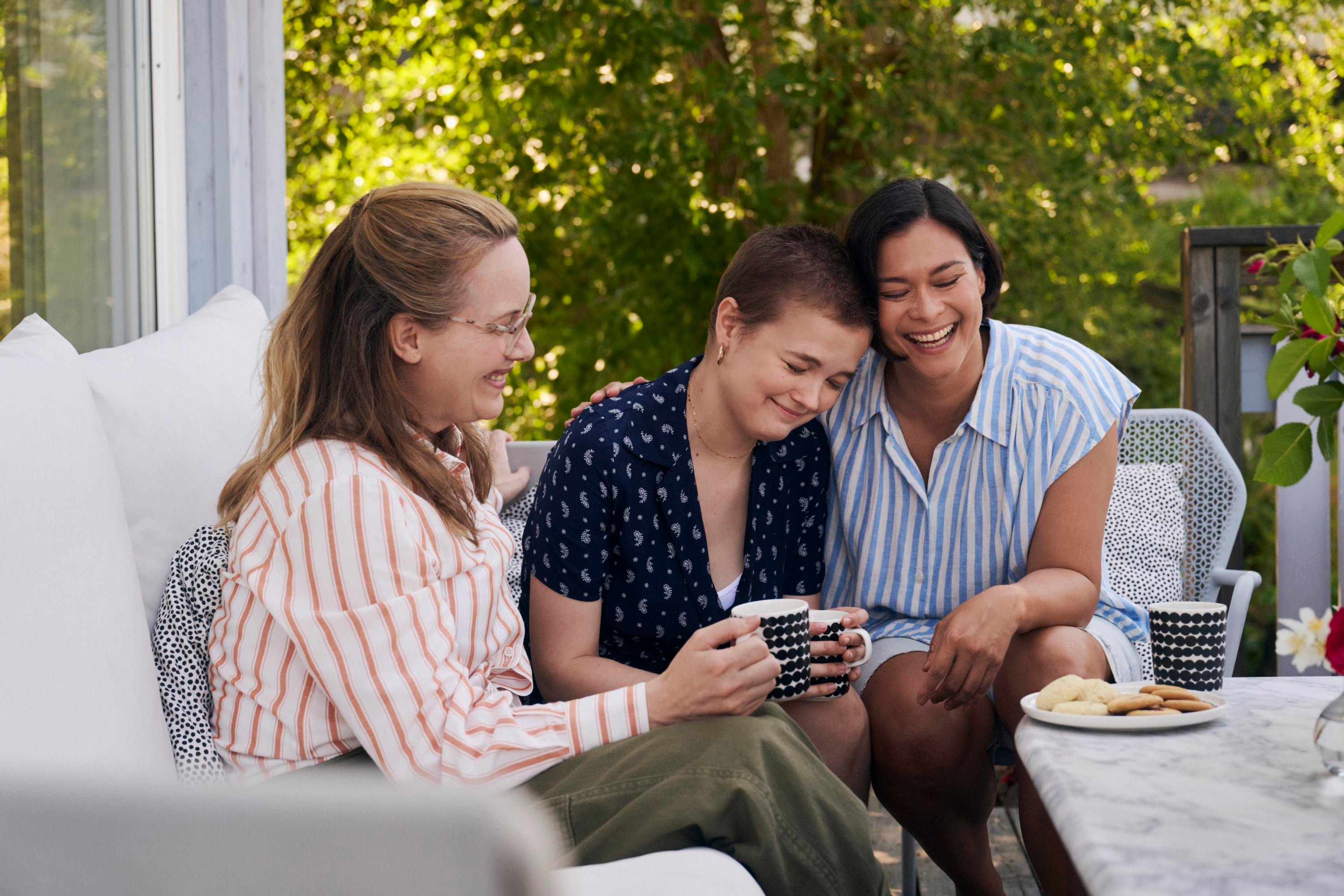 Tre kvinnor dricker kaffe på en uteplats