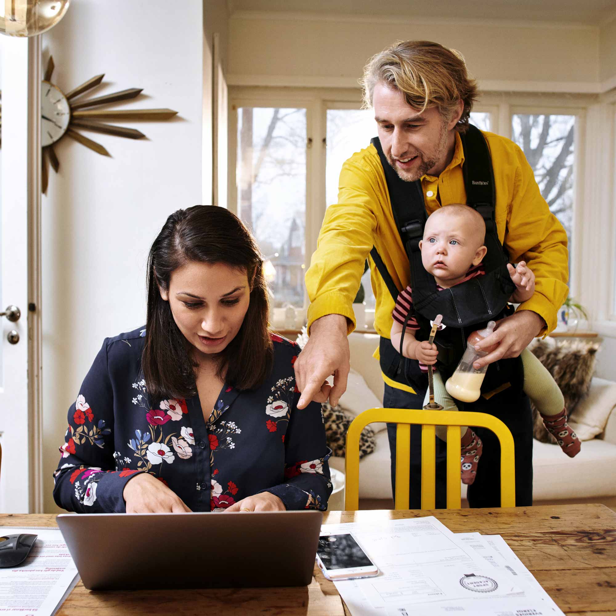 Ett par med en bebis tittar på en laptop.